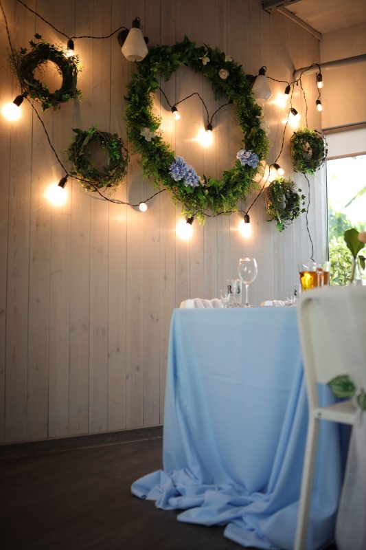 Свадебное оформление зала в кафе «Оранжерея», с живыми и искусственными цветами, ретро гирляндой, чехлами на стулья.