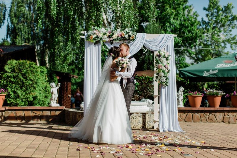 Оформление свадебной арки для выездной регистрации композицией из живых цветов и украшение свадебного зала в кафе. План рассадки для гостей.